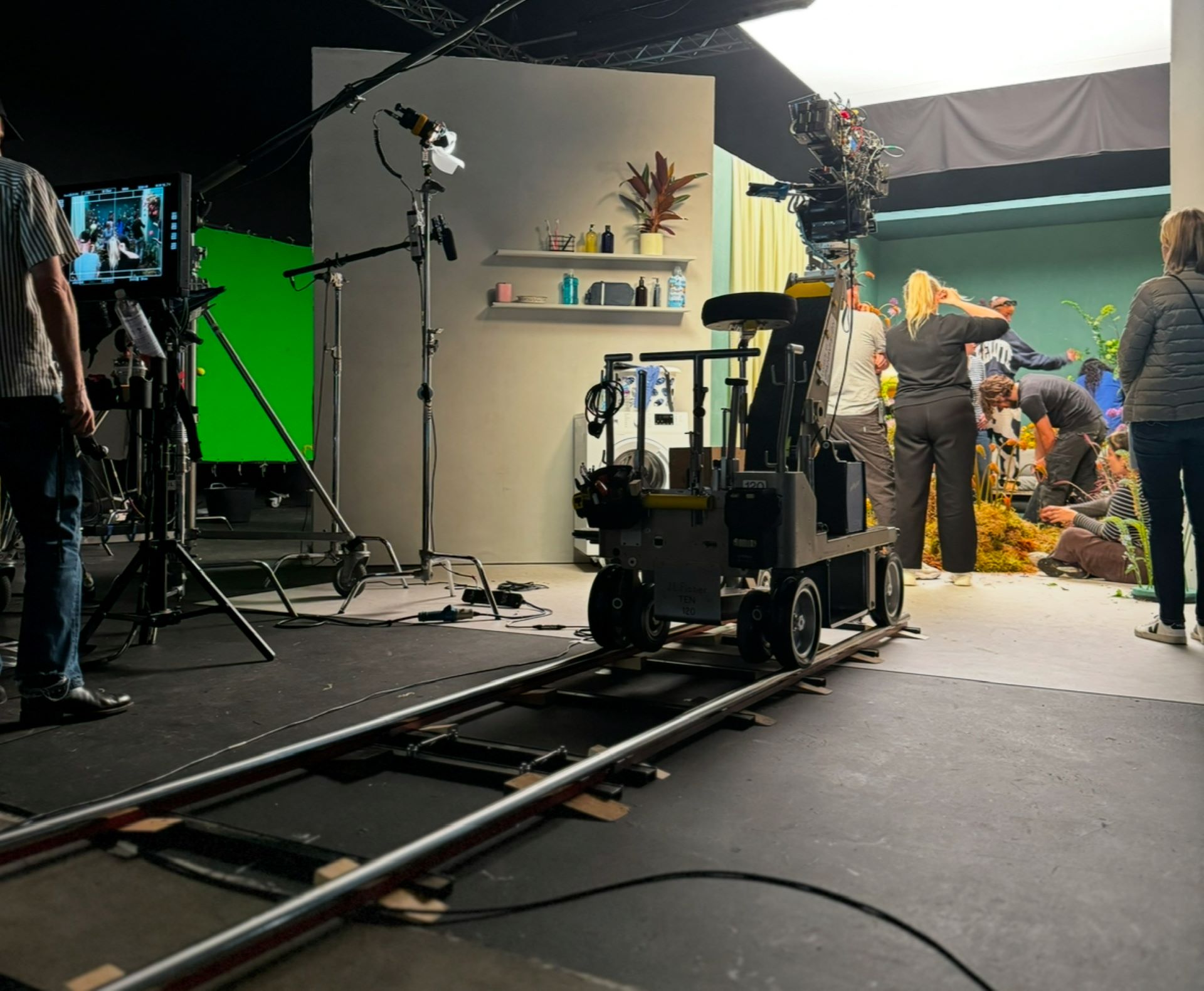 An indoor film set with a dolly in the centre and a team dressing the set