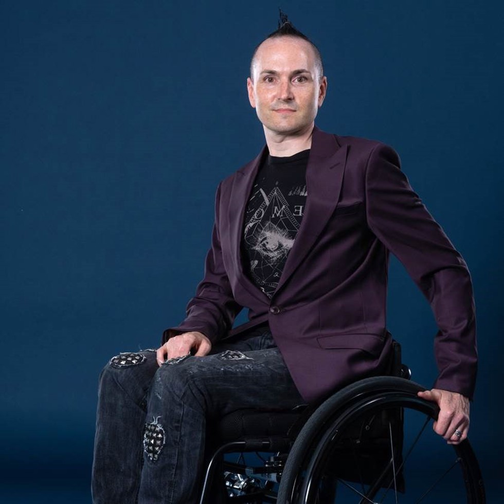 Director Owen Tooth sits on a wheelchair and looks towards the camera