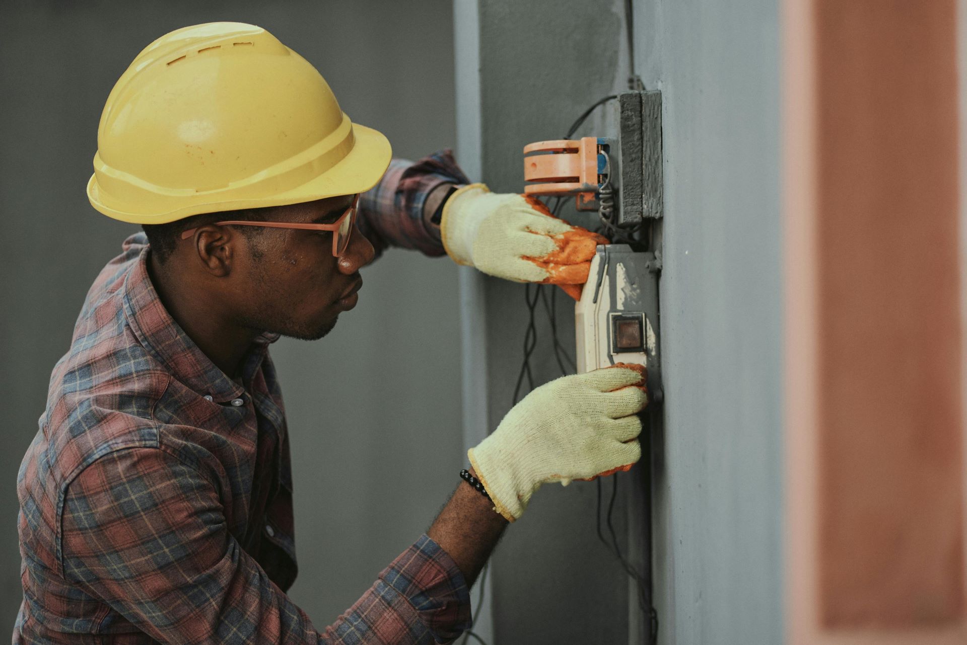 An electrician rewiring a fuse board on a wall