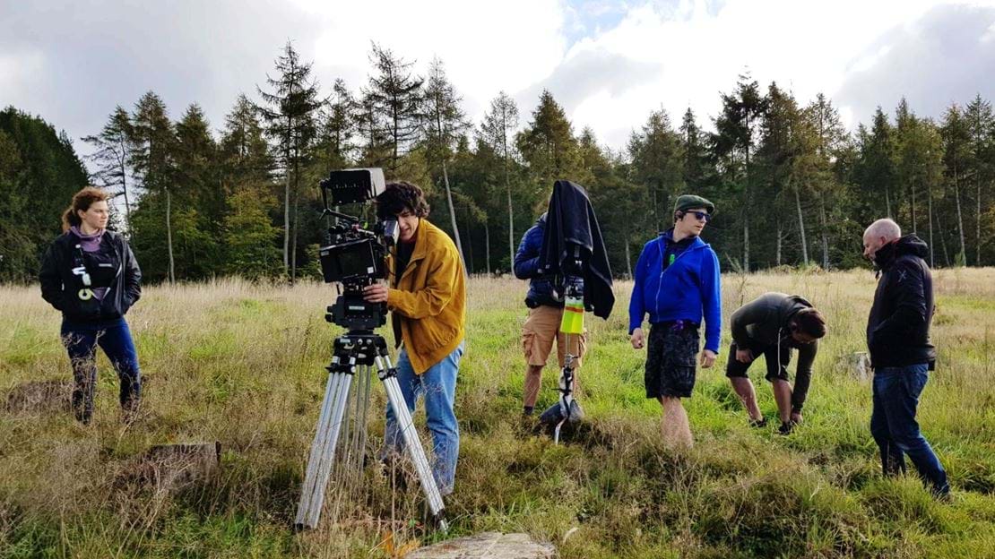 Camera crew standing in a grassy area 