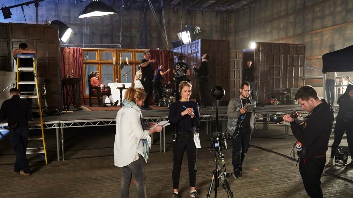 Four people stand around a 360 camera rig on set