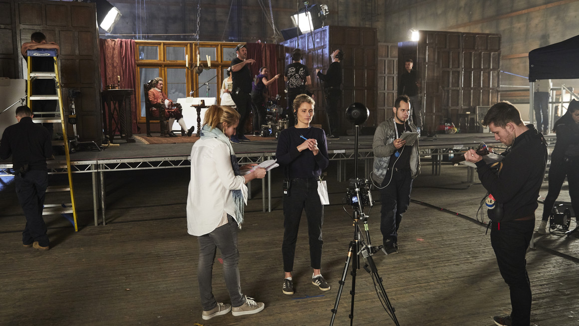 Four people stand around a 360 camera rig on set