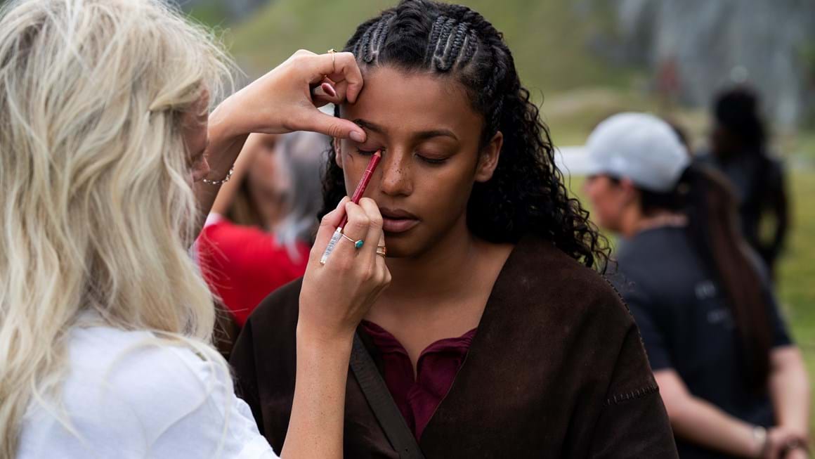 Woman applies eyeliner to female actress on location