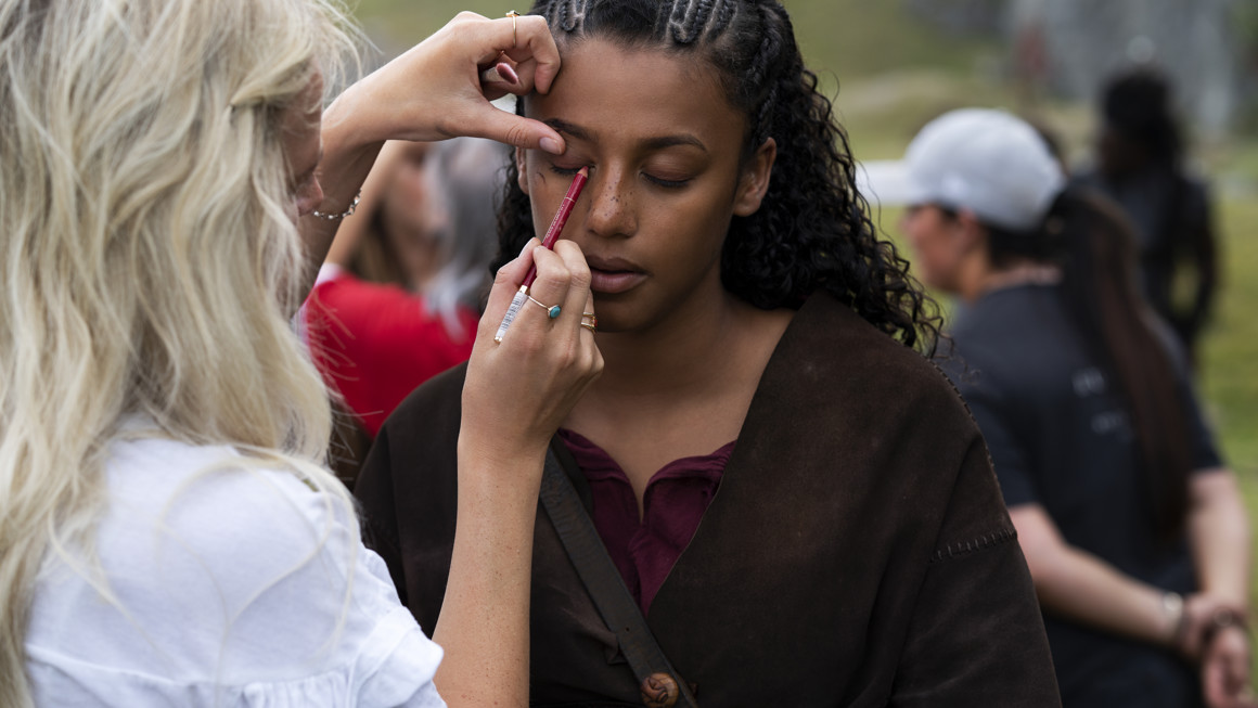 Woman applies eyeliner to female actress on location