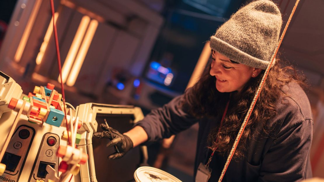 Woman wearing gloves painting part of the set on the set of Doctor Who