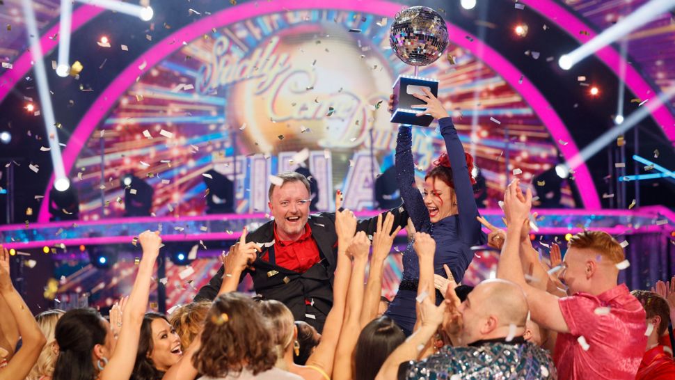 Production shot of Strictly Come Dancing 2024 winners being held aloft with the glitterball trophy