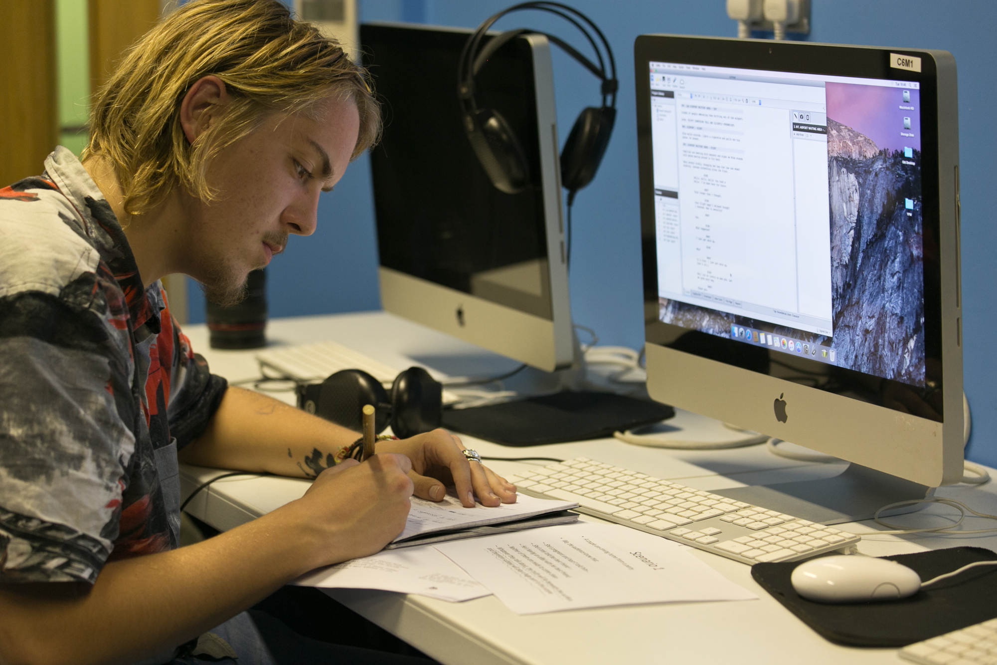 Man writing on a document in front of a computer screen