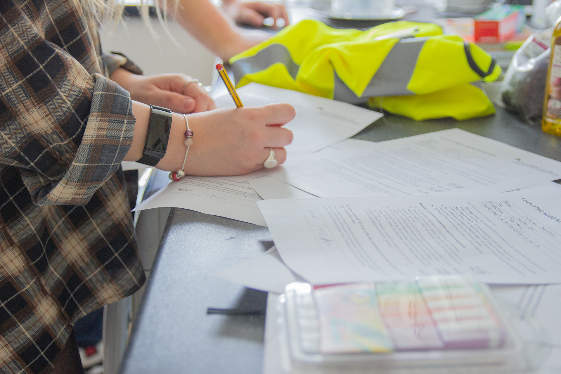 Close up of person signing document next to high vis jacket
