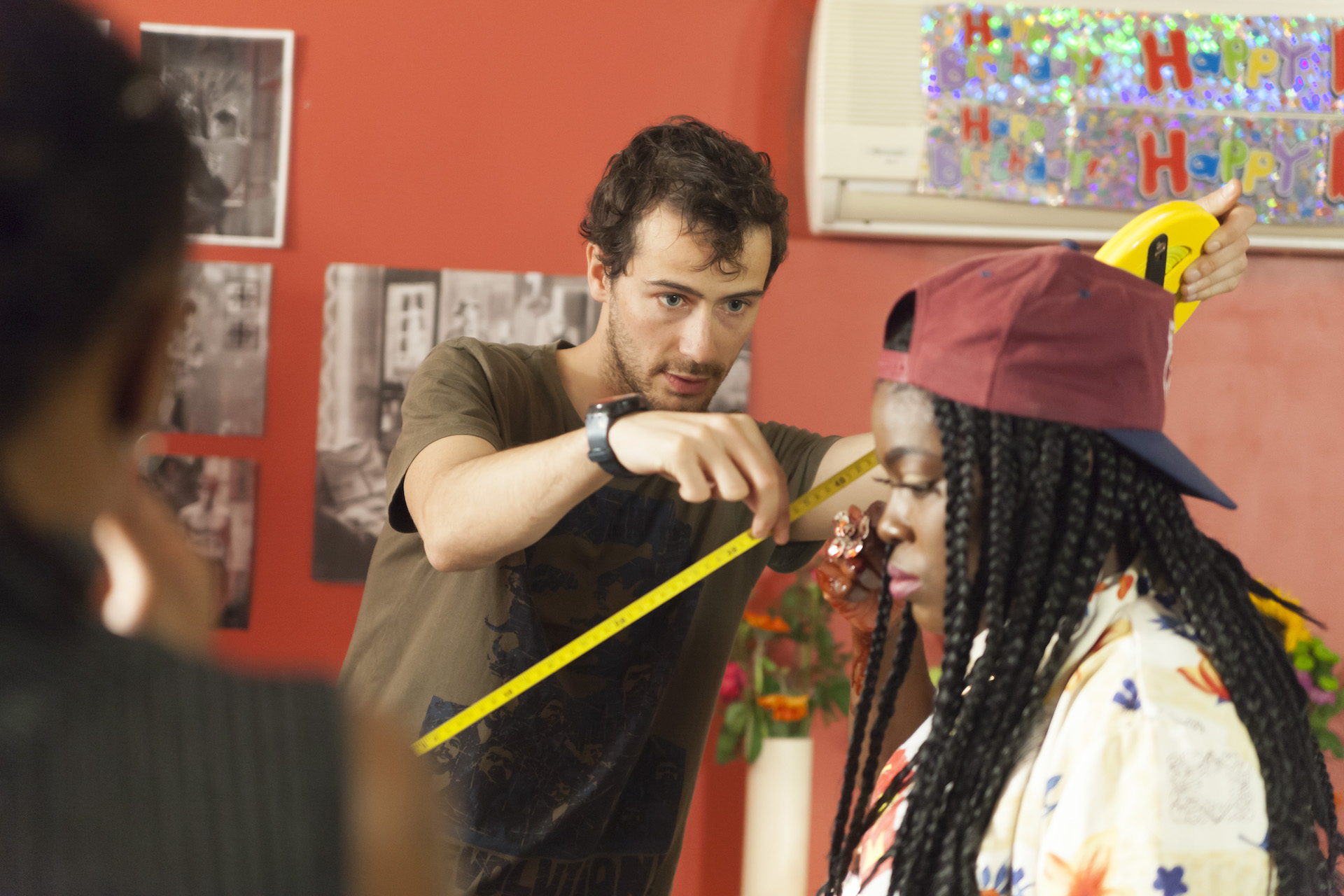 Young man holding measuring tape next to seated young woman