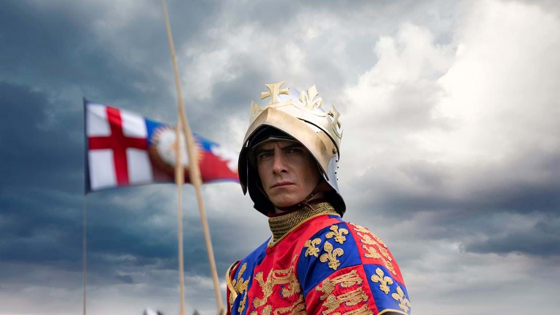 Actor dressed as a king on a horse with flag in background