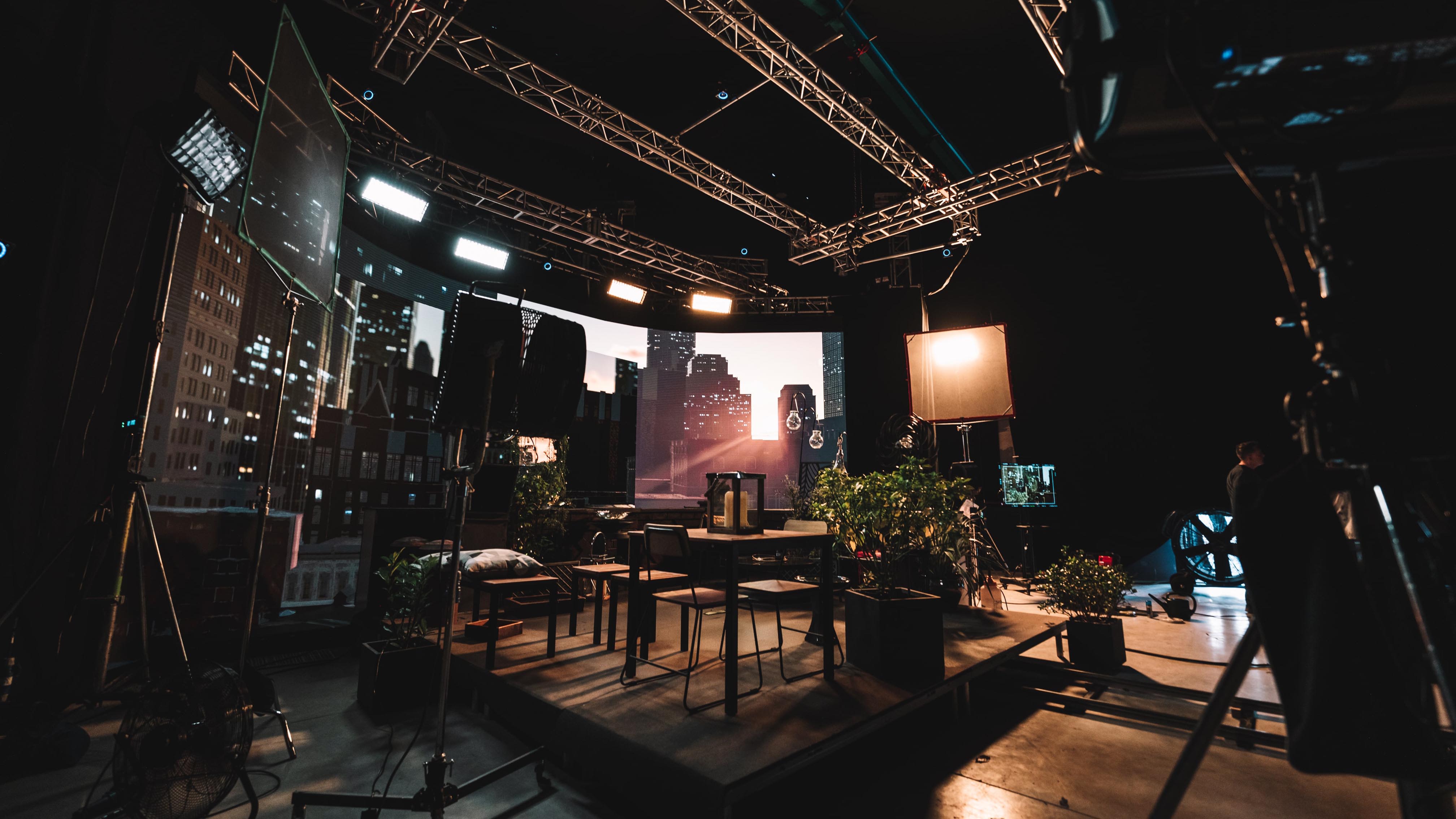 A  fictional living room in front of a virtual production screen showing a skyscraper background