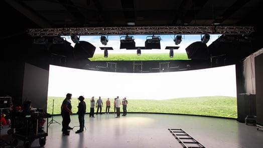 Crew in front of a virtual production screen showing a hill