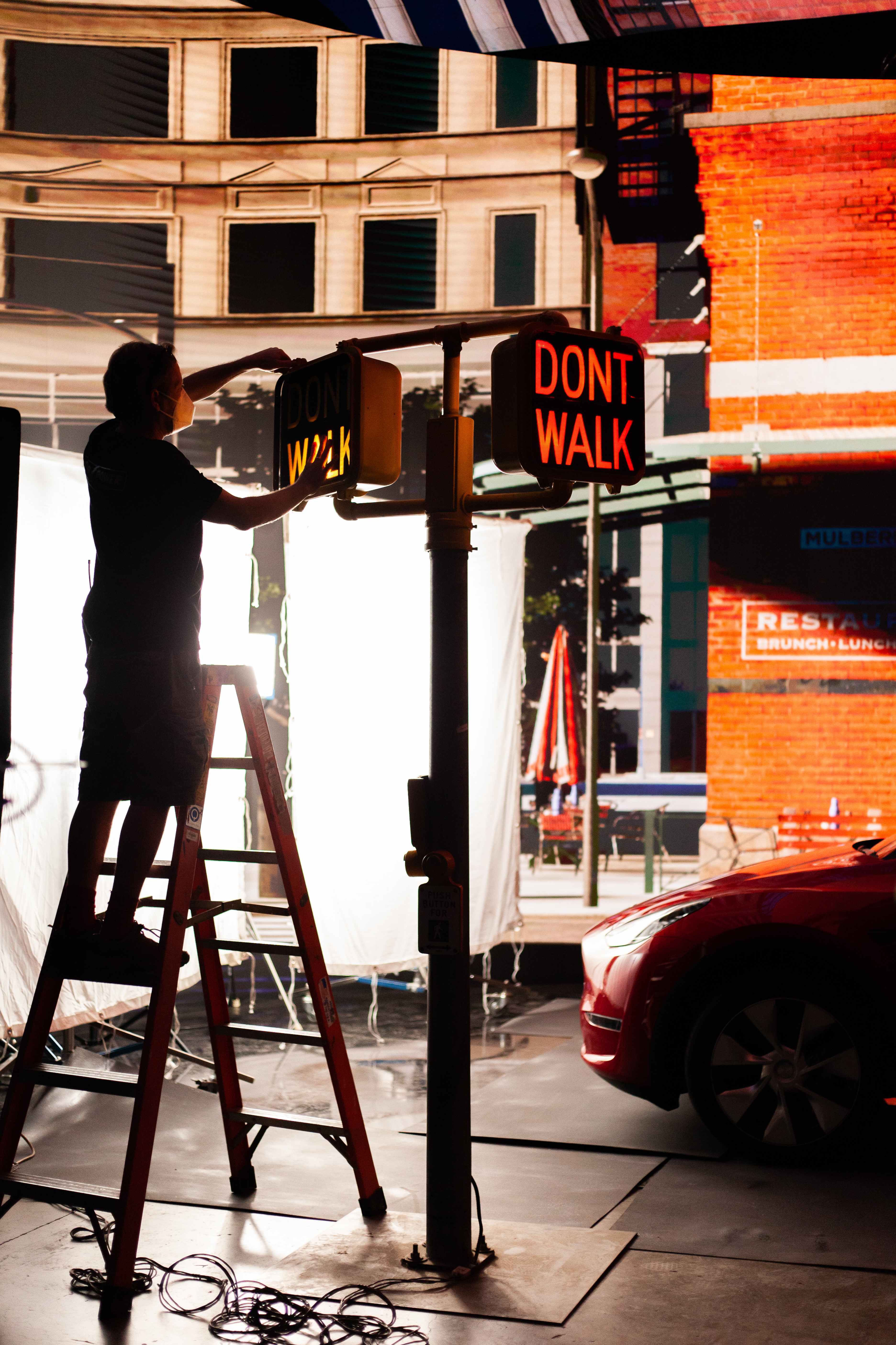Member of crew setting up traffic lights in front of a virtual production screen showing New York streets
