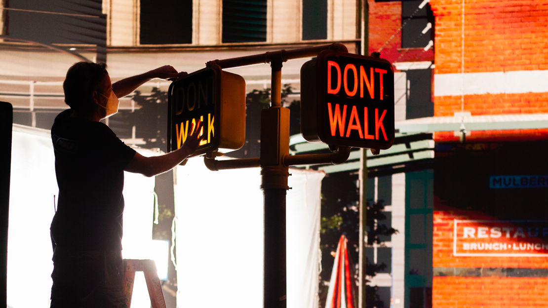 Member of crew setting up traffic lights in front of a virtual production screen showing New York streets