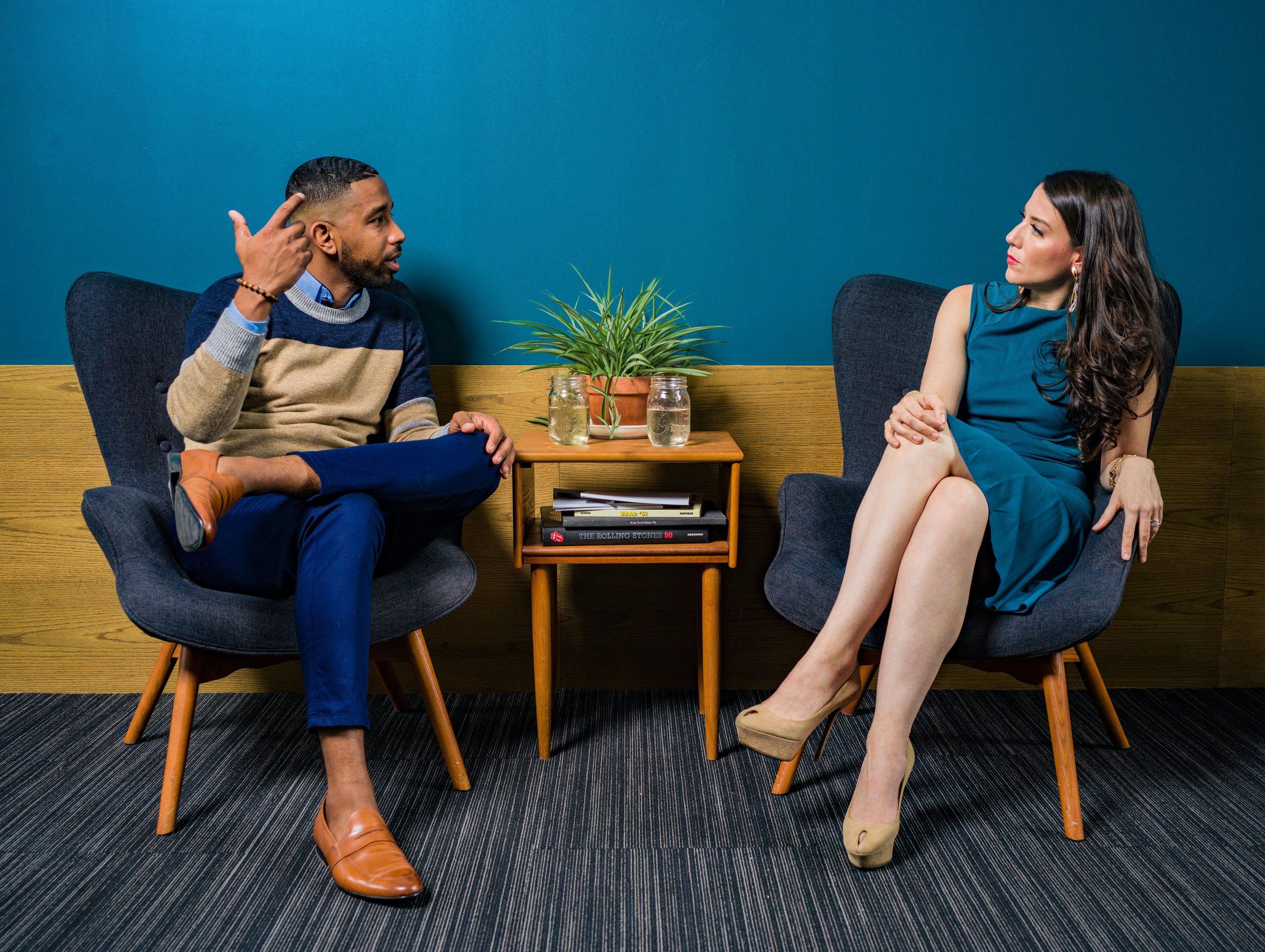 A young man and a young woman sat at a coffee table in conversation
