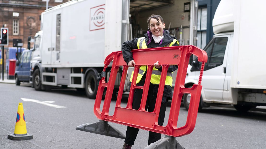 Assistant in high-visibility vest lifting portable fence