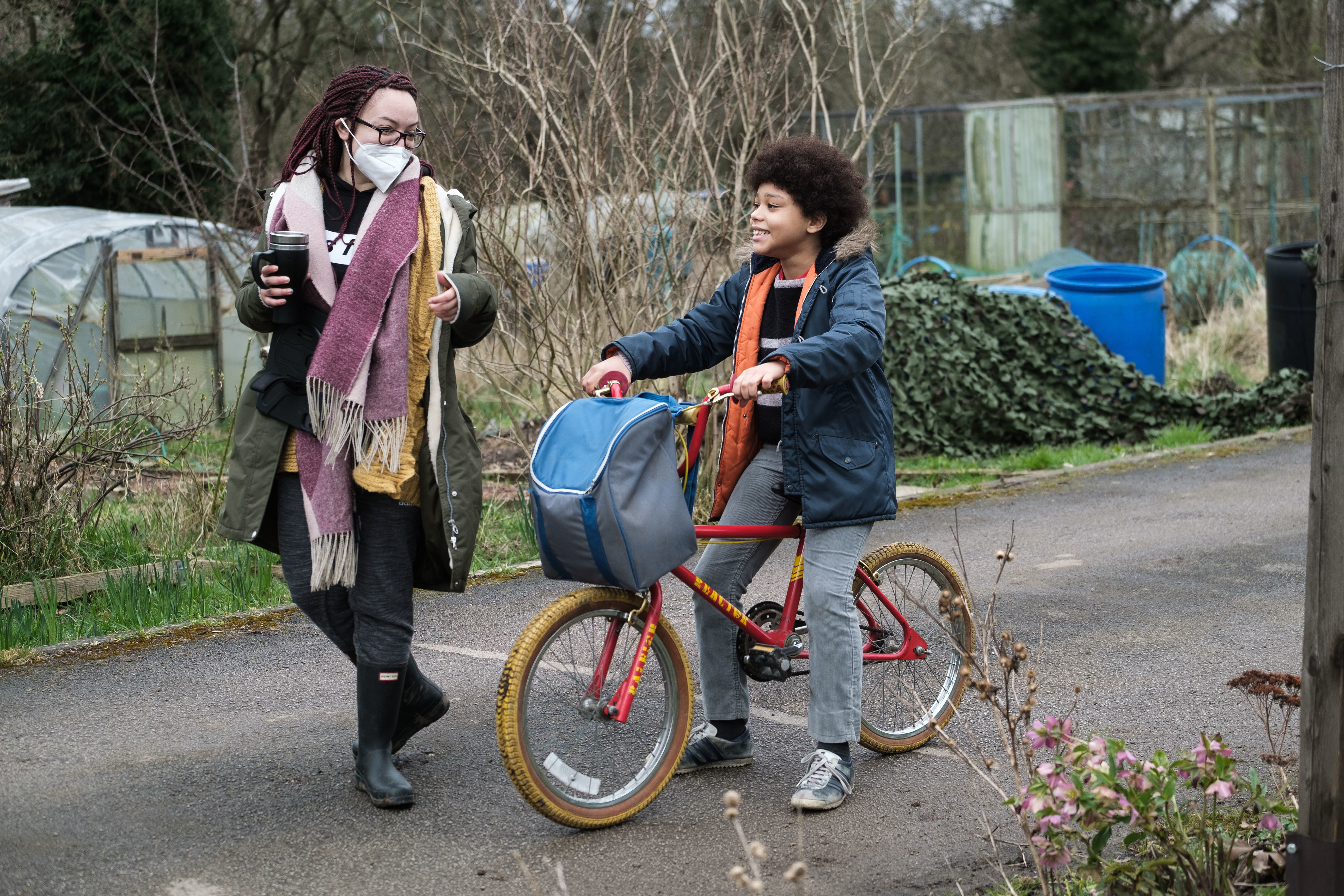 A director walks beside an actor on a bicycle