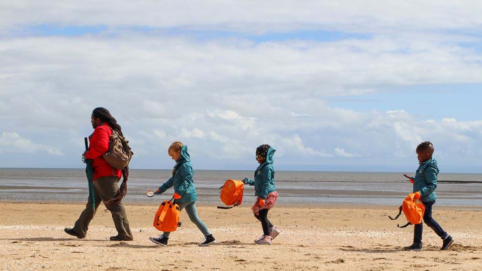 Production shot from Ranger Hamza's Eco Quest S2 of Ranger Hamza (Hamza Yassin) and his three young ramblers march along the beach
