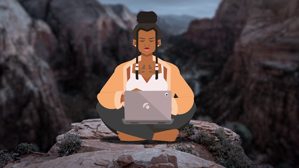 person sitting cross-legged on a rock typing on a laptop