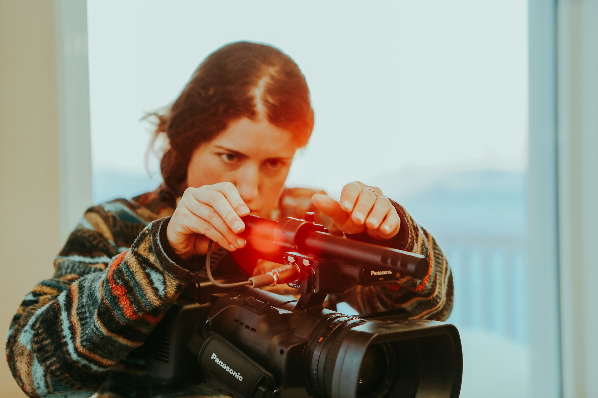 A sound assistant fixes a microphone onto a large camera.