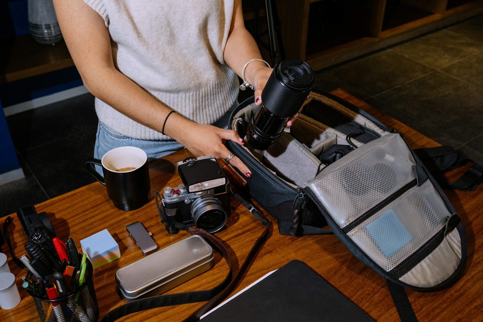 A photo of a table full of camera equipment, pens and stationary