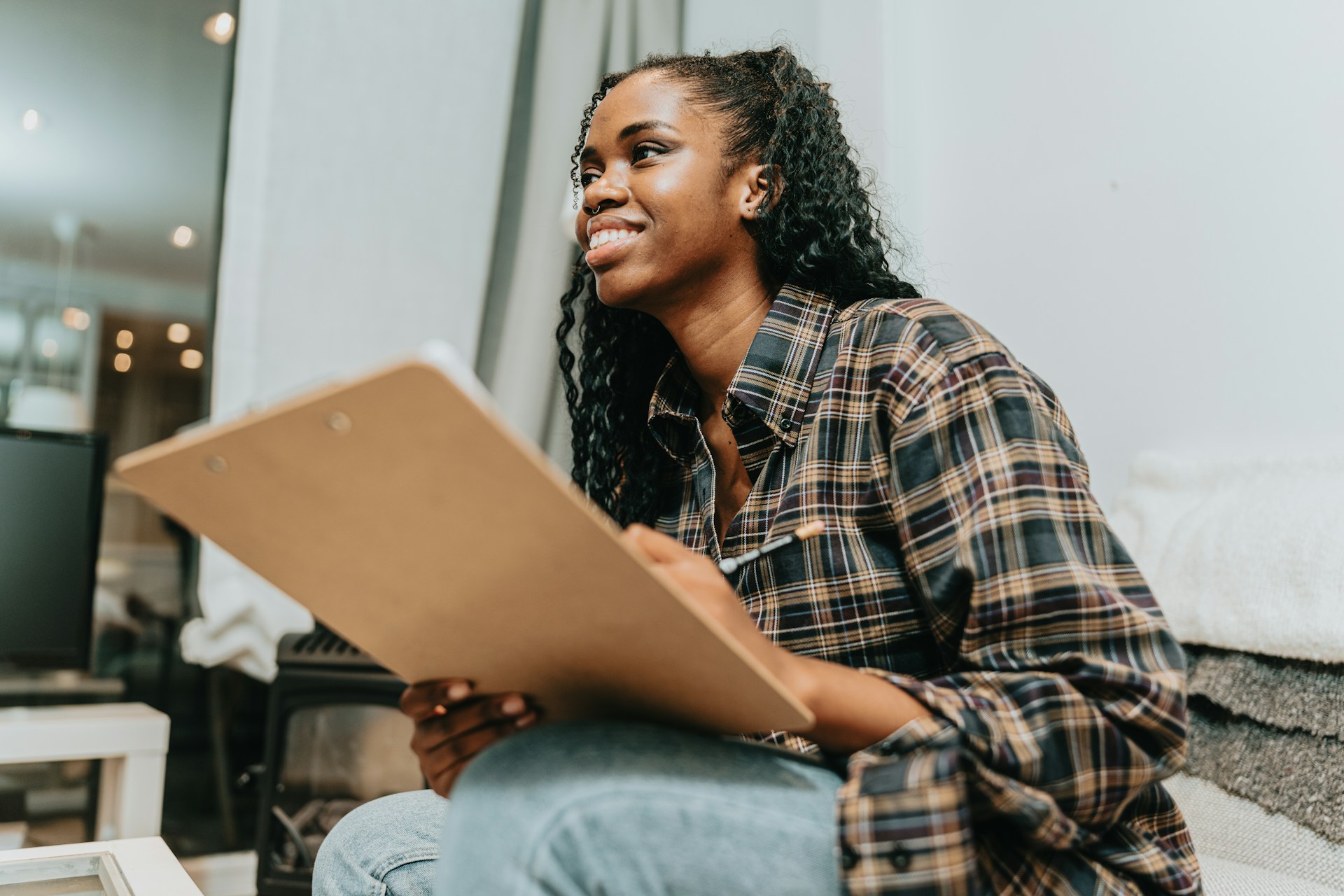 A woman sits writing on a clipboard