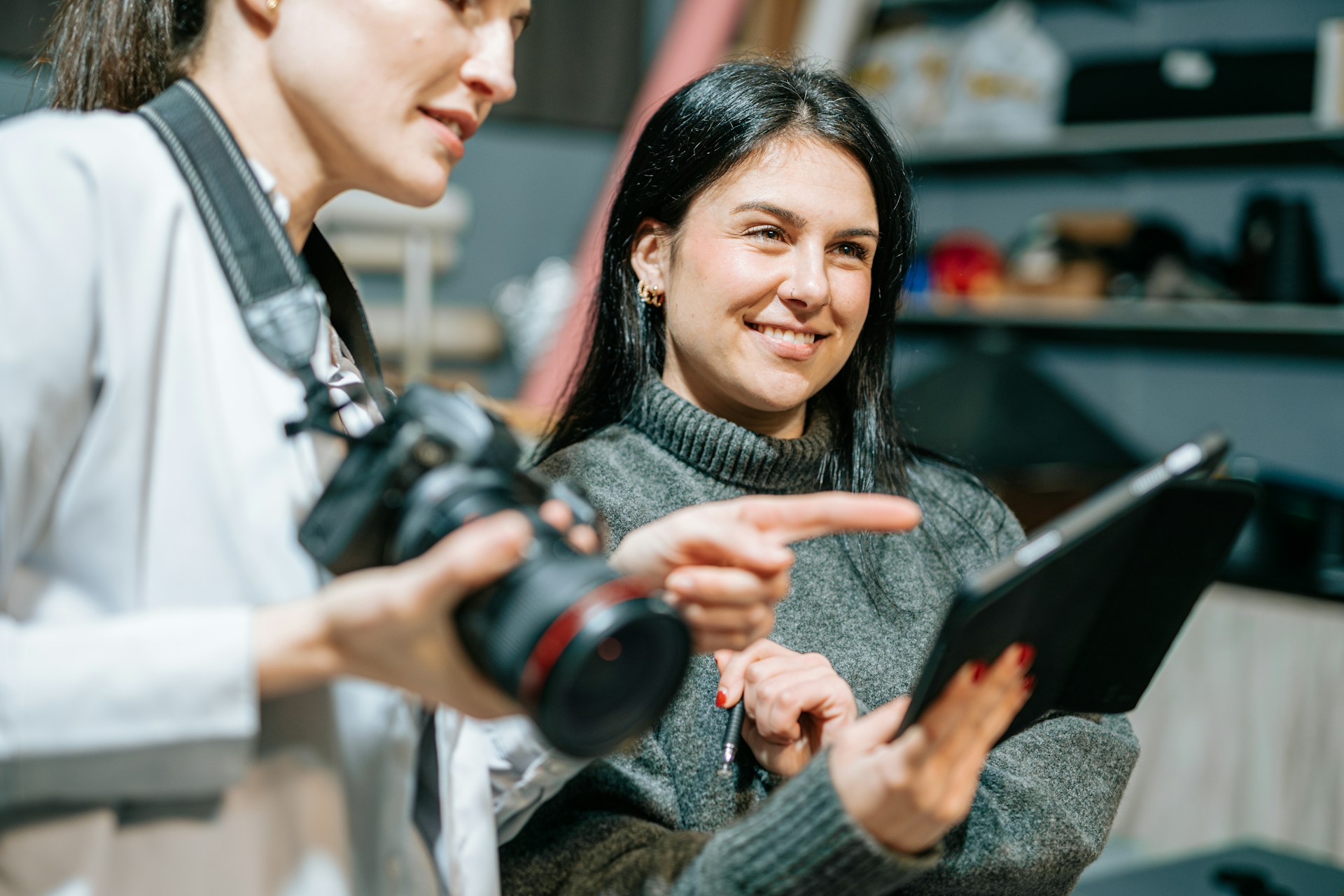 A photographer holding a camera stands next to a producer holding an iPad