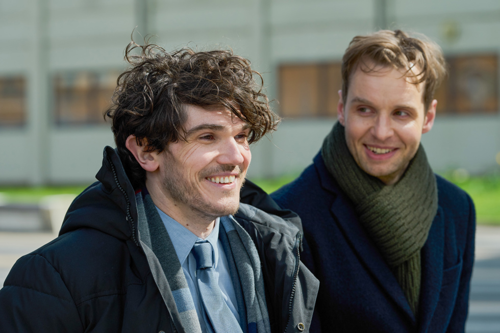 Two men share a smile while sitting outside