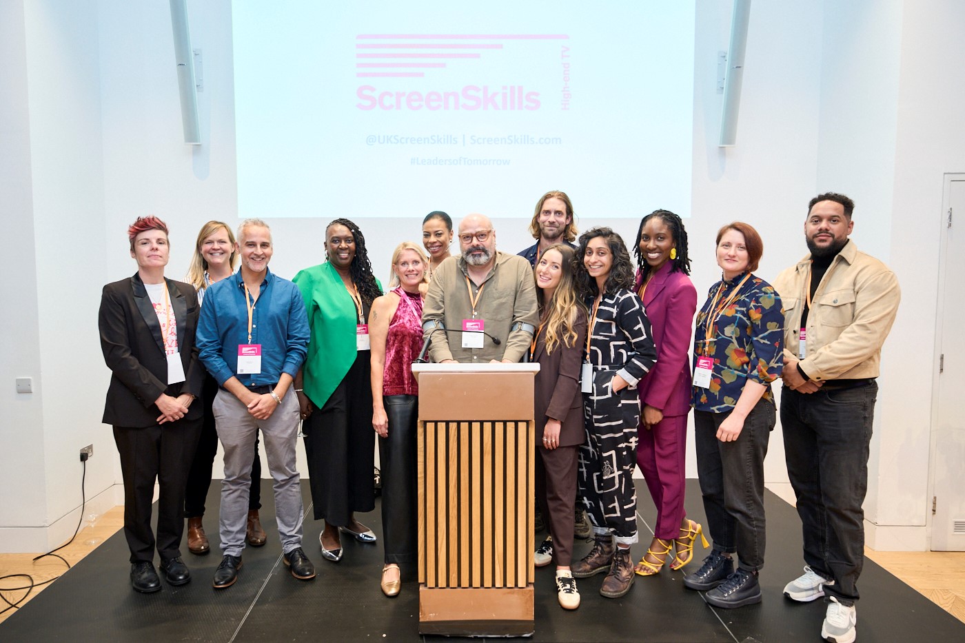 Group photo of the Leaders of Tomorrow cohort one standing around a lectern at their graduation ceremony