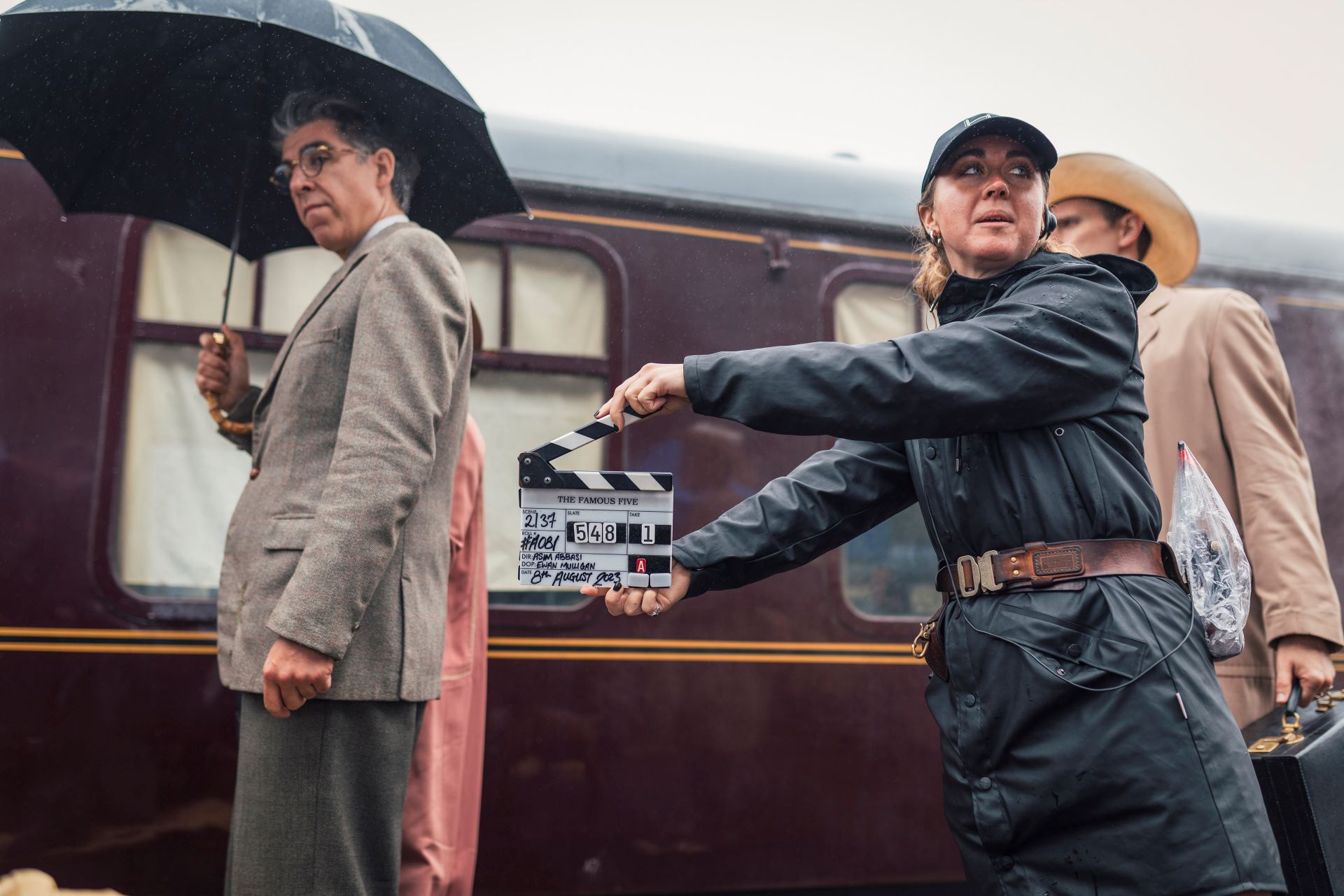 A member of production crew shuts a clapperboard on set