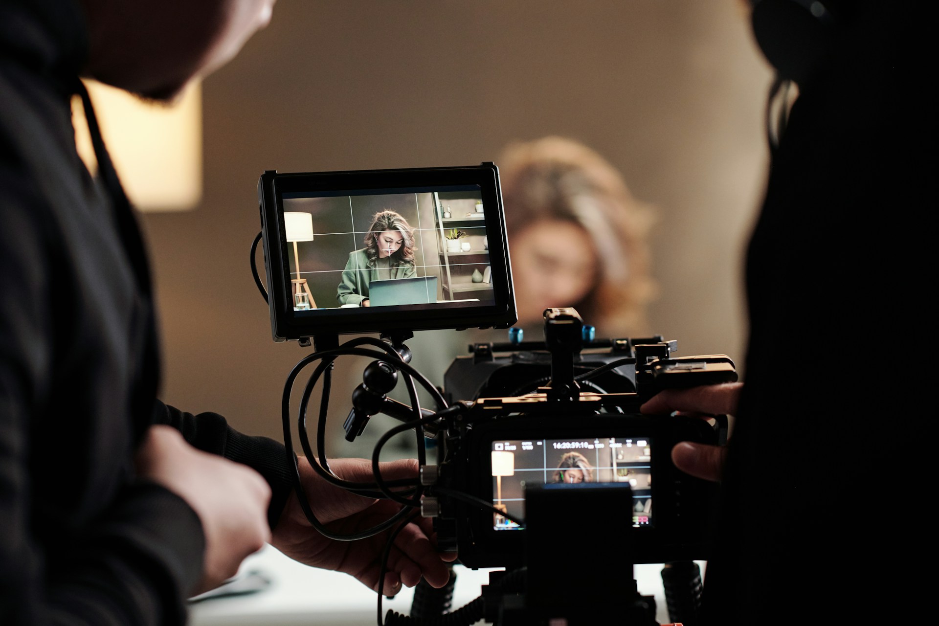 A closeup of a camera monitor on set with two people standing either side of it