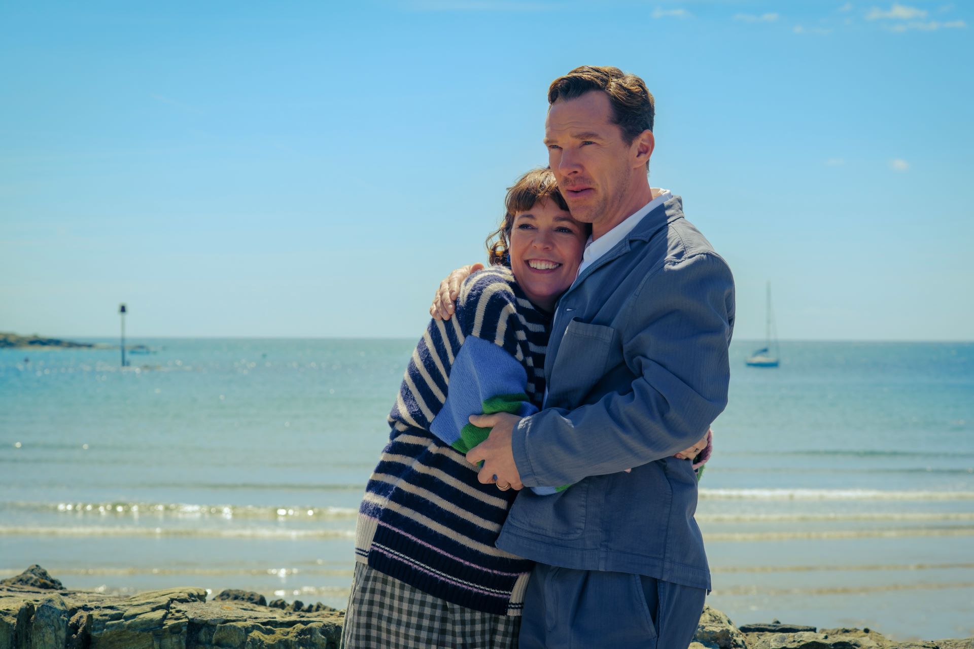 Olivia Colman and Benedict Cumberbatch embracing on a beach