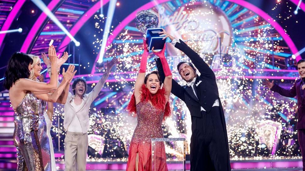 Dancing partners lift the Strictly trophy in front of cheering contestants and fireworks