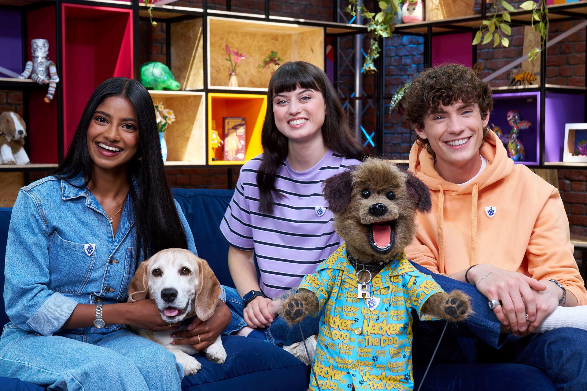 Four people sit on a sofa with a dog and Hacker T Dog smiling at the camera