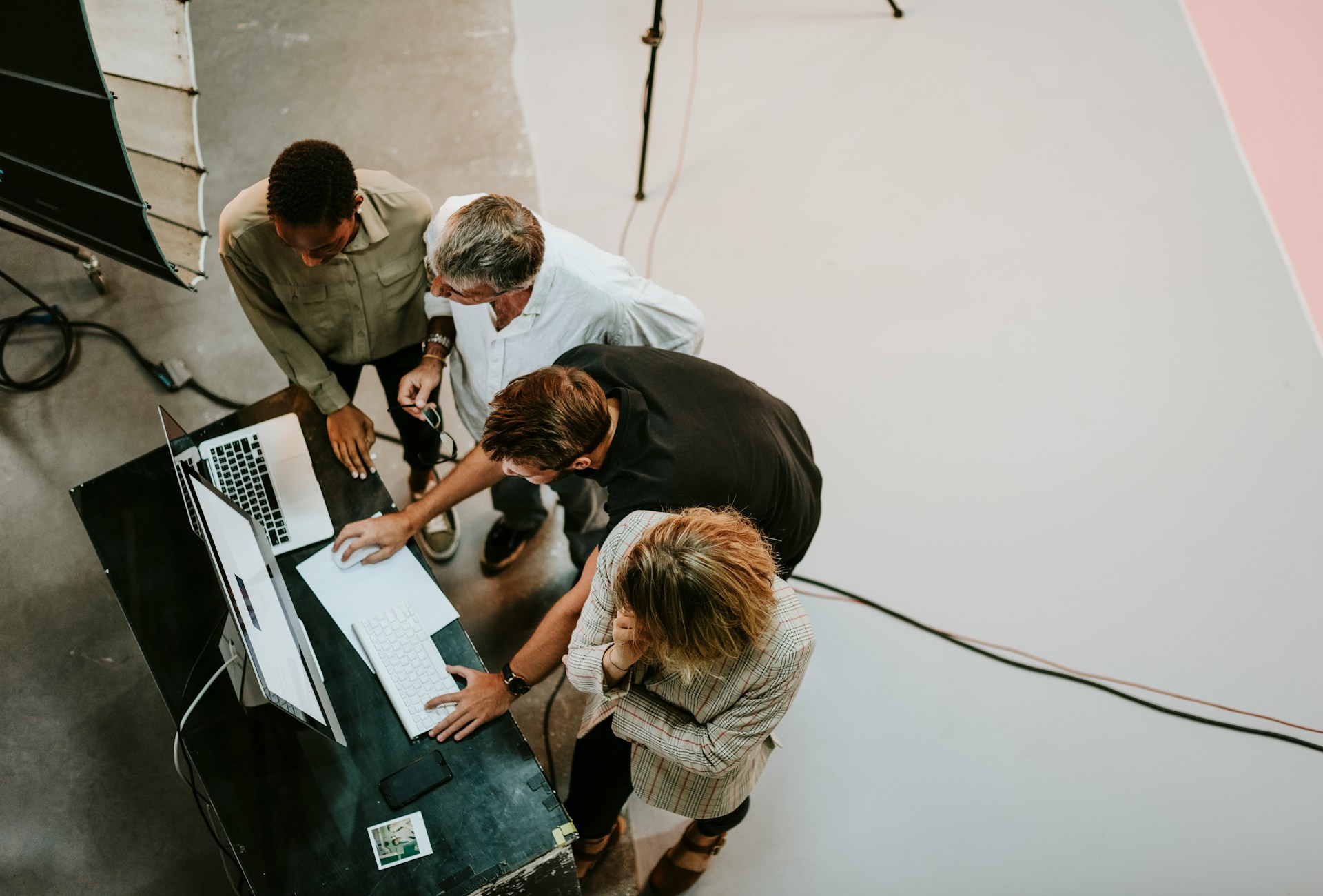 A group of people stand around a desk looking at a computer monitor