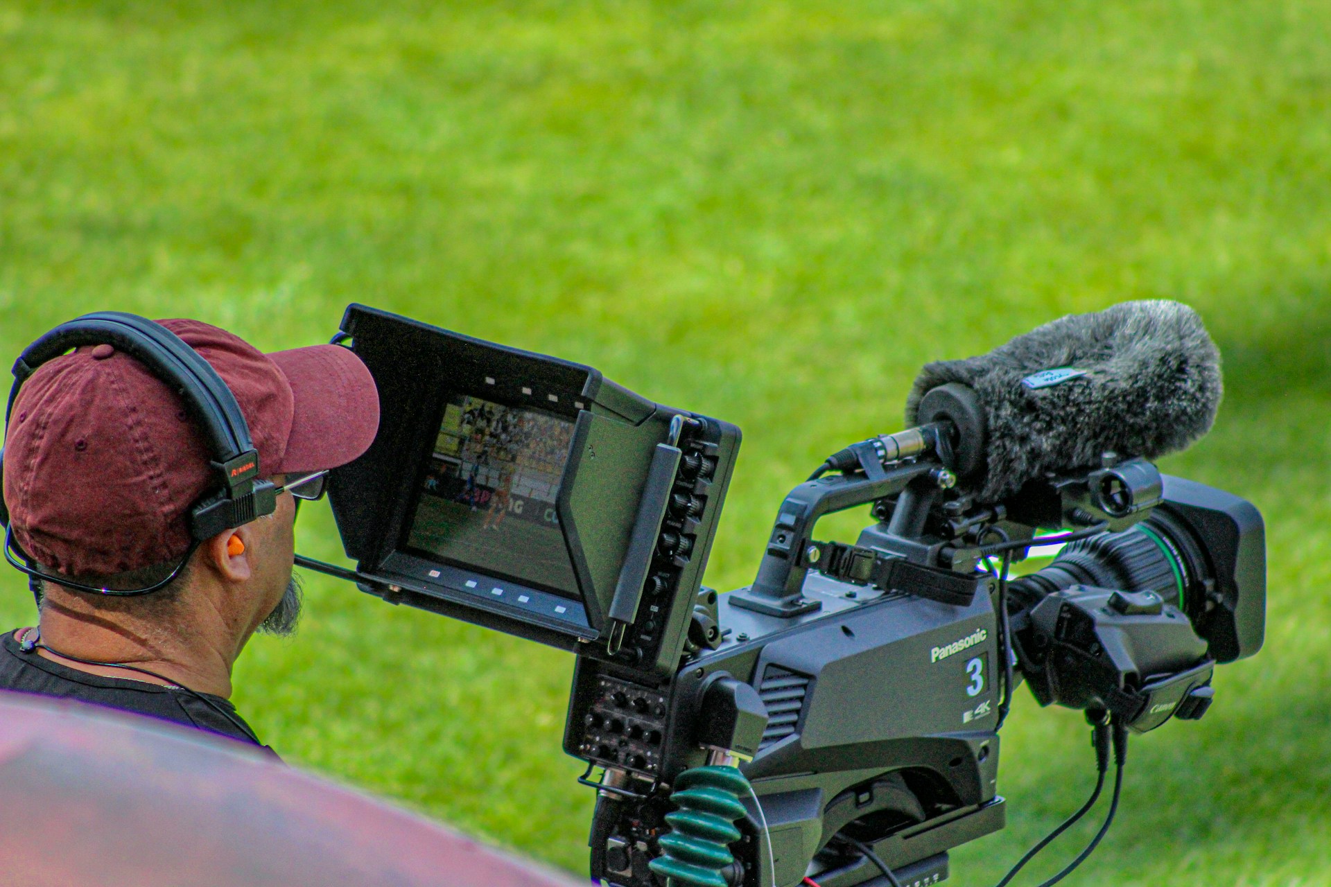 A camera operator sits looking through a large monitor on a cinema camera