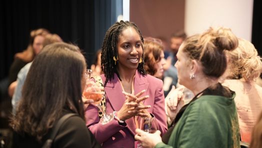 Graduating candidate Rianna Charles smiles as she speaks with two other guests at the Leaders of Tomorrow graduating event in London